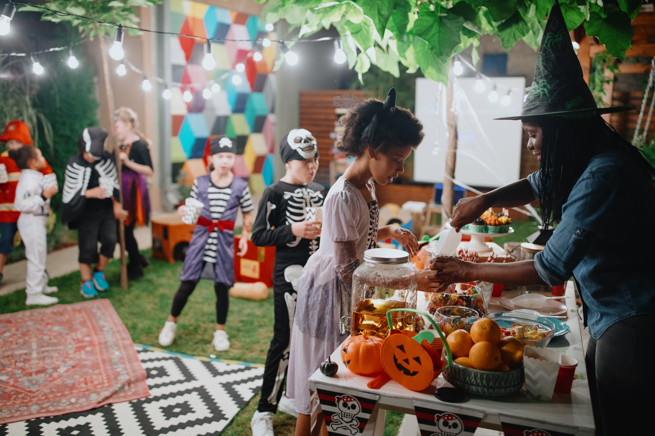 Parent serving candy and popcorn to her kids and their friends at backyard movie night Parent serving candy and popcorn to her kids and their friends at backyard movie night