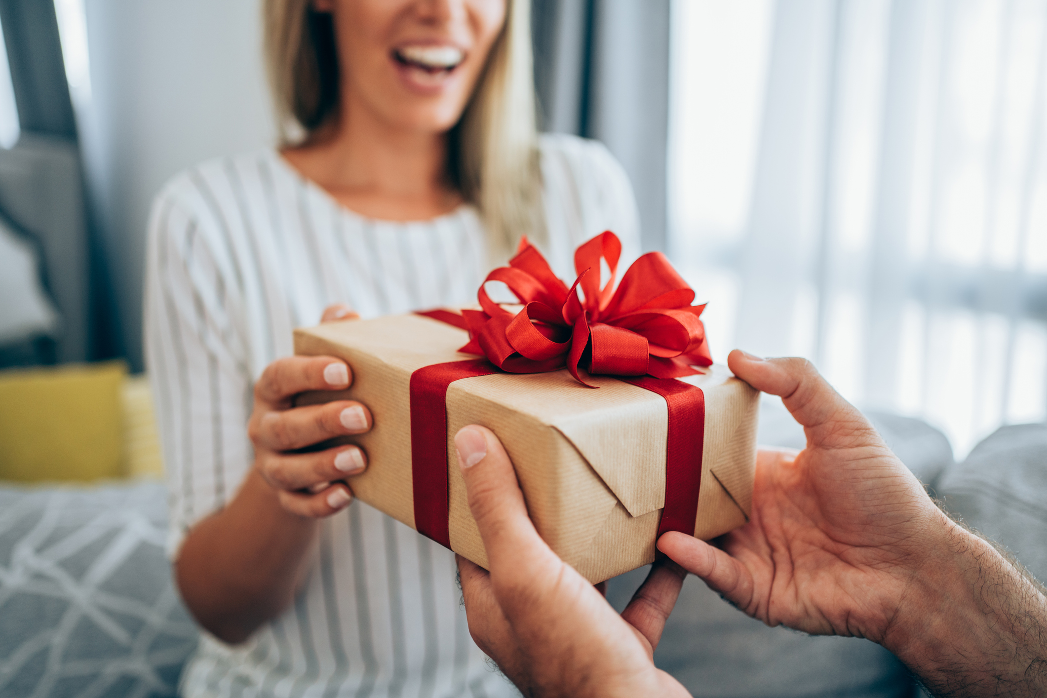 Cheerful young woman receiving a gift from her boyfriend. Cheerful young woman receiving a gift from her boyfriend.