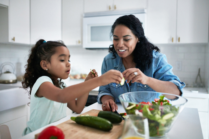 Girl learning to prepare meal from mother