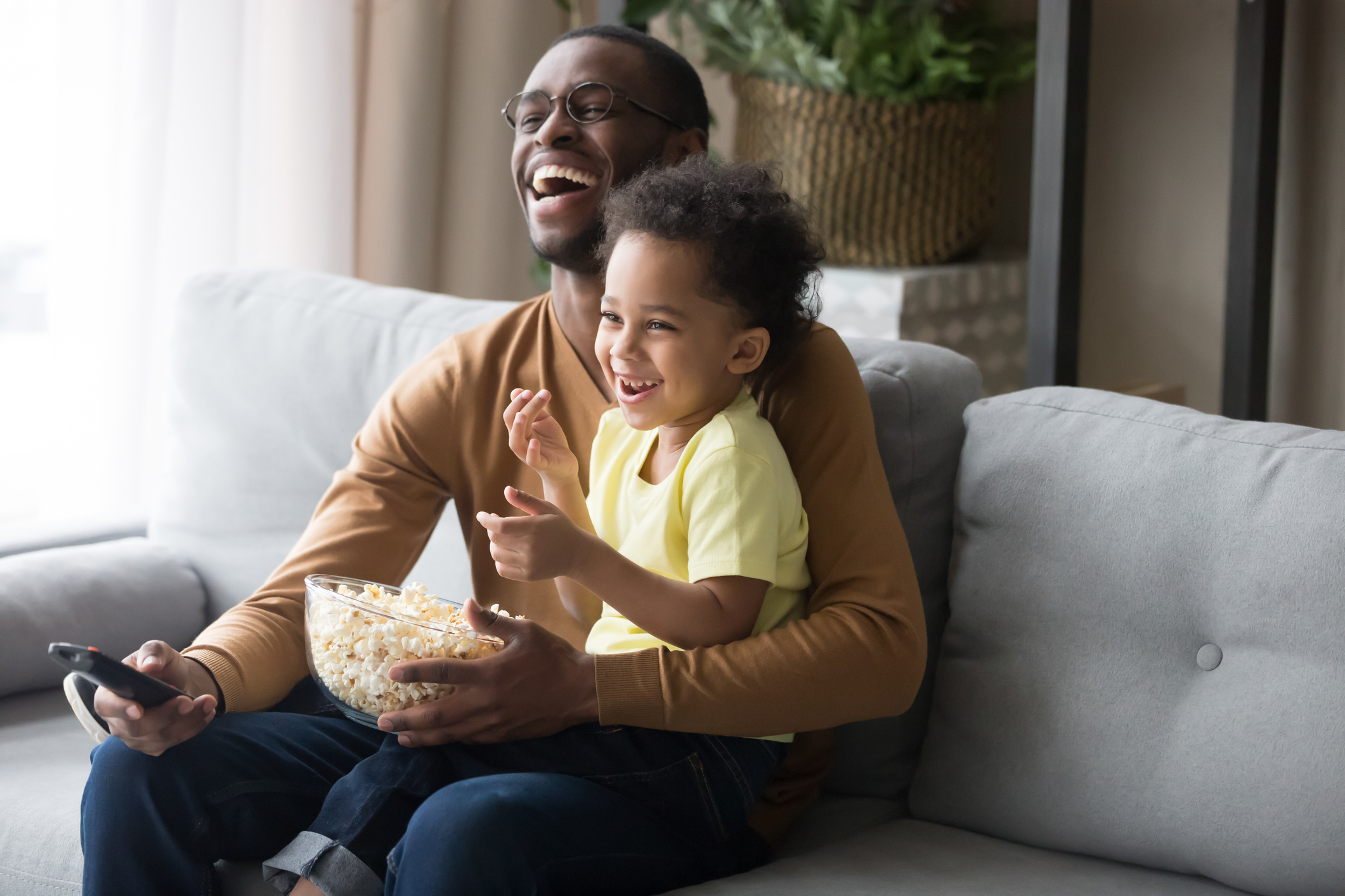 Happy african dad and kid son laughing watching funny comedy